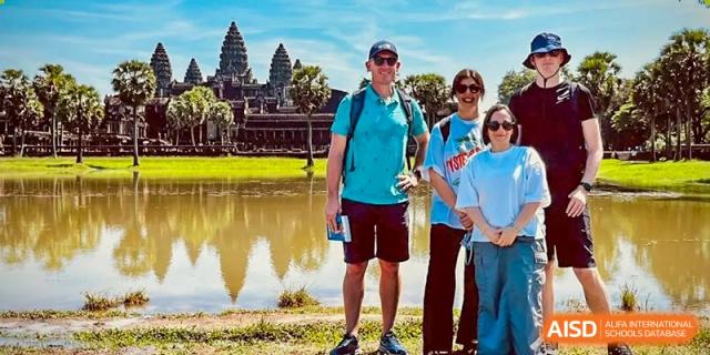 Students and an adult from Dulwich International High School Programme Hengqin (DHHQ) posing for a photo during a field trip, with a historical temple site (resembling Angkor Wat) in the background.