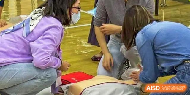 Students from Dulwich International High School Programme Hengqin (DHHQ) observing or participating in First Aid training, with a practice dummy visible.