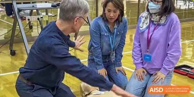 An instructor at Dulwich International High School Programme Hengqin (DHHQ) demonstrating the proper technique for chest compressions to a female student during a CPR/First Aid lesson.