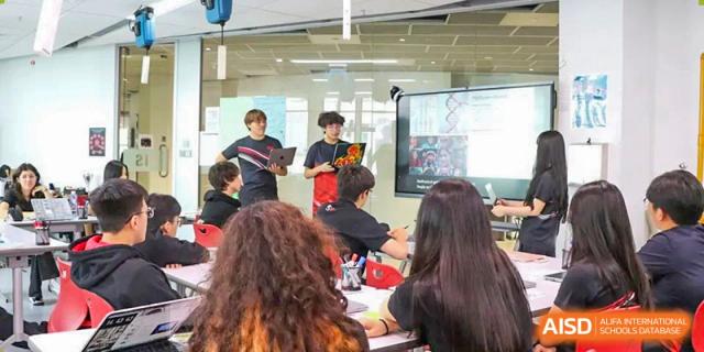 A group of middle school students engaged in a presentation and discussion in a classroom at Shekou International School.