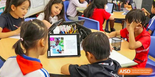 Elementary students collaboratively learning using a digital tablet during a technology lesson at Shekou International School.