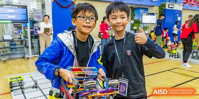 Two students showcasing colorful, self-made projects at a fair or exhibition event held at Shekou International School.