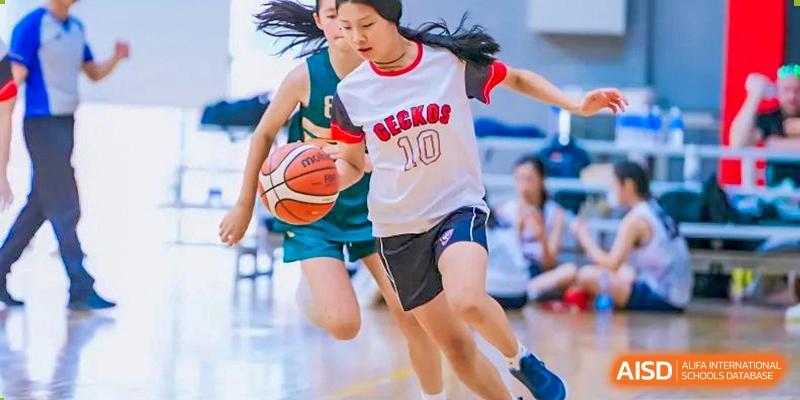 An intense action shot of two female students competing for the ball during a fast-paced basketball game at Shekou International School.