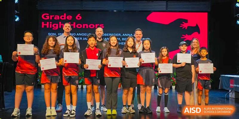 A group of high-achieving students from Shekou International School on stage with staff, proudly holding their academic honor certificates.