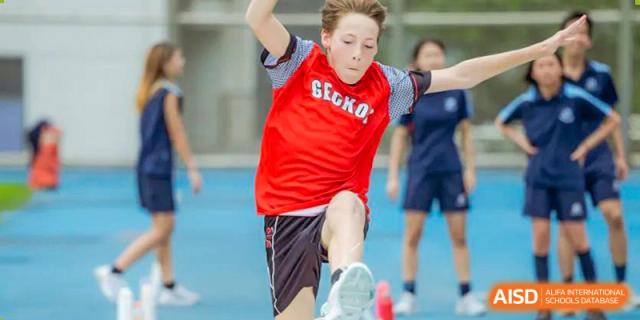 An intense close-up of a student in a red shirt playing soccer/football during a sports day at Shekou International School.