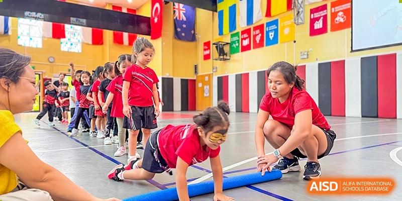 Young students participating in a challenging physical activity or obstacle course indoors at Shekou International School.