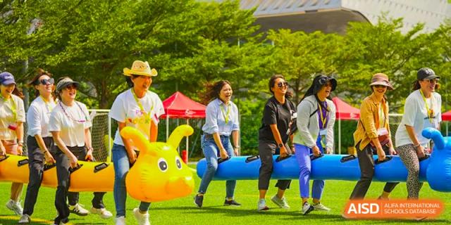 Students playing a fun outdoor game with an inflatable toy at Shekou International School, clearly enjoying the spirit of a community event.