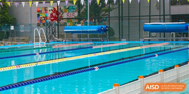A wide shot of the bright, clean outdoor swimming pool facility, with lane dividers, located at Shekou International School.