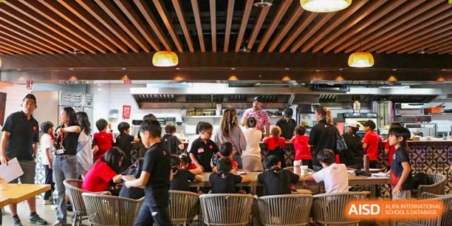 Students and staff gathering in a busy, modern cafeteria during lunch or a community event at Shekou International School.