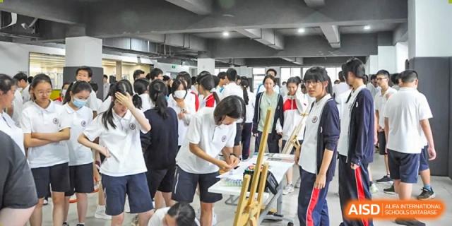 Students in uniform participating in an indoor activity, possibly a band practice or performance, at Shanghai Nanyang Model Private School.