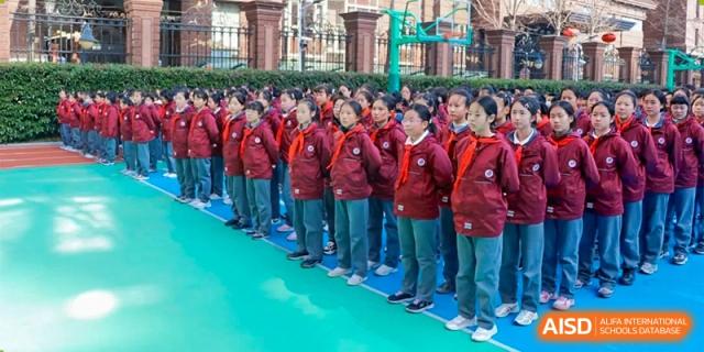 A line of students in red jackets and uniforms standing ready outdoors for an event or ceremony at Shanghai Nanyang Model Private School.