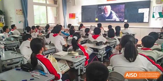 Students seated in a classroom watching a video or presentation displayed on a large screen at Shanghai Nanyang Model Private School.