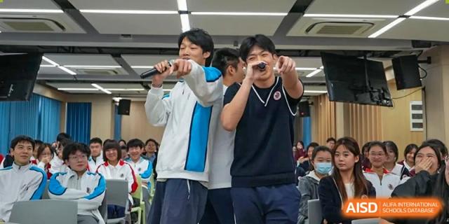 Two male students singing or performing with microphones during a school event or talent show at Shanghai Nanyang Model Private School.