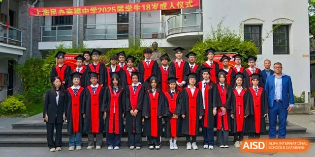 A group of students wearing graduation gowns and caps posing outdoors in front of a school building at Shanghai Nanyang Model Private School.