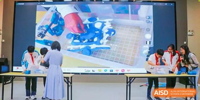 A close-up of a hands-on project (blue and white model) being demonstrated on a large interactive screen in a classroom at Shanghai Nanyang Model Private School.