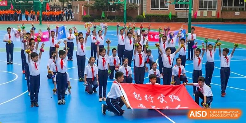 A large group of students in red ties and white shirts holding a red banner during an outdoor event or ceremony at Shanghai Nanyang Model Private School.
