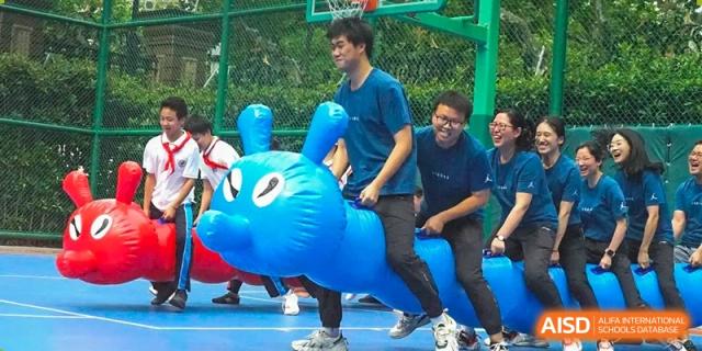 A student riding a large blue inflatable animal during an outdoor fun activity or event at Shanghai Nanyang Model Private School.