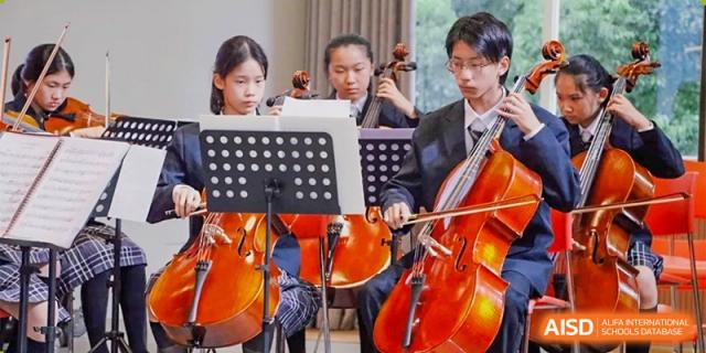 Students performing in a small string ensemble (cello and violins) at a musical event at Shanghai Nanyang Model Private School.