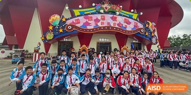 A large group of students posing together in front of a colorful, decorated backdrop at Shanghai Nanyang Model Private School.