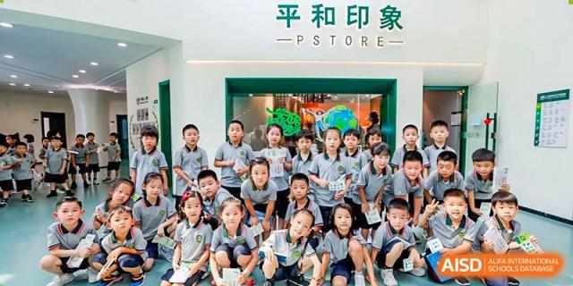 A large group of Shanghai Pinghe School primary students in uniform posing together outside the school store, labeled "和平印像 P-STORE."