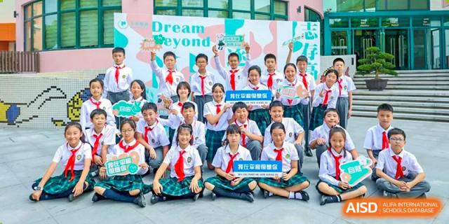 A large group of Shanghai Pinghe School students posing happily in uniform in front of a banner that reads "Dream Beyond."