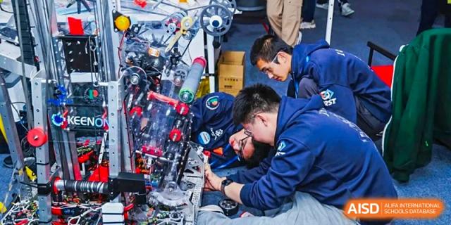 A small group of Shanghai Pinghe School students, primarily males, work together to assemble or repair a complex robotics or machinery project.