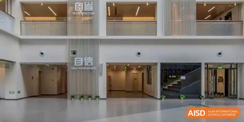 Interior view of a brightly lit school hallway with a wide entrance and a sign with Chinese characters, signifying the modern architecture of Shanghai Pinghe School.