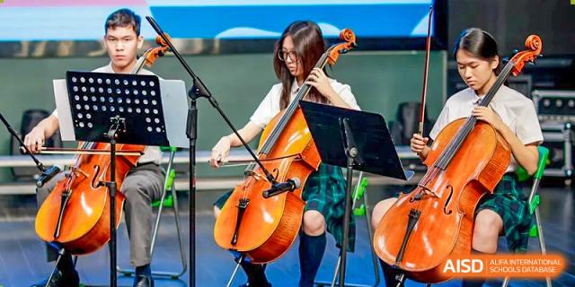 A student in a plaid skirt playing a cello with sheet music on a stand at Shanghai Pinghe School.