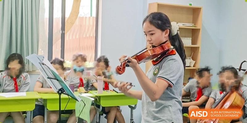 A girl with a ponytail playing a violin indoors at Shanghai Pinghe School.