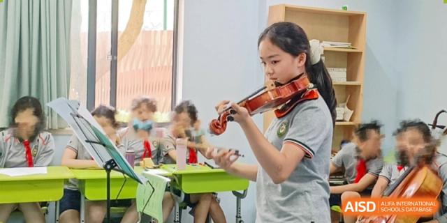 A girl with a ponytail playing a violin indoors at Shanghai Pinghe School.