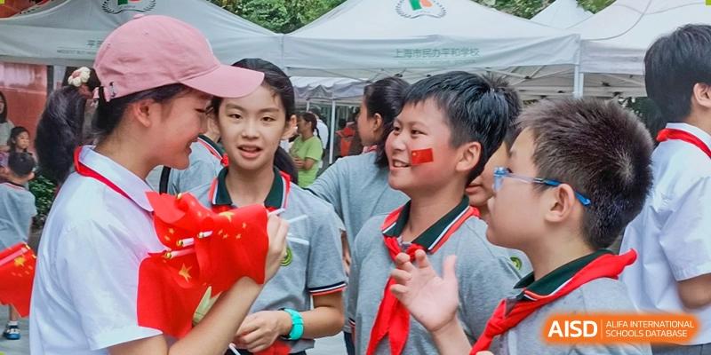Two students with painted faces smiling during an outdoor event or celebration at Shanghai Pinghe School.