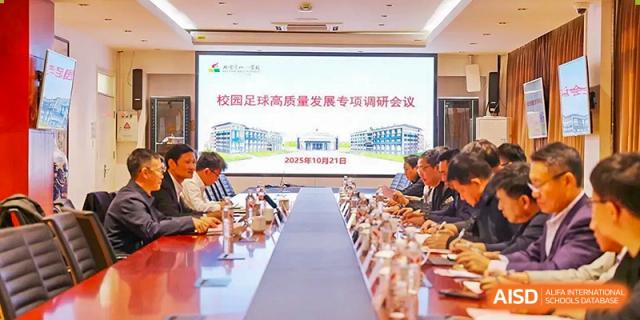 An administrative meeting or conference taking place at Beijing Bayi School International Department, with people seated around a long table facing a large screen displaying school information and architecture.