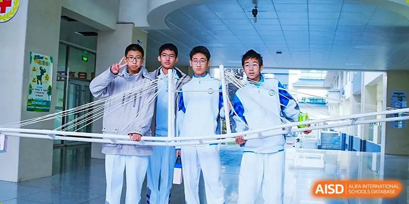 A group of four male students from the Beijing Bayi School International Department posing together in their white and blue uniforms, possibly after a competition or event.