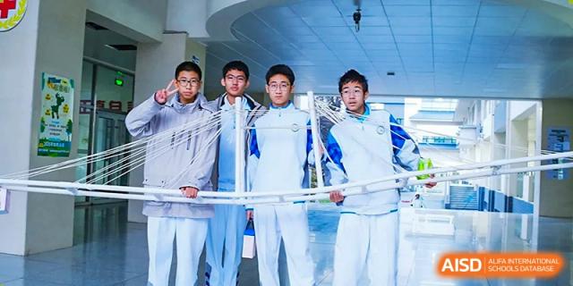 A group of four male students from the Beijing Bayi School International Department posing together in their white and blue uniforms, possibly after a competition or event.