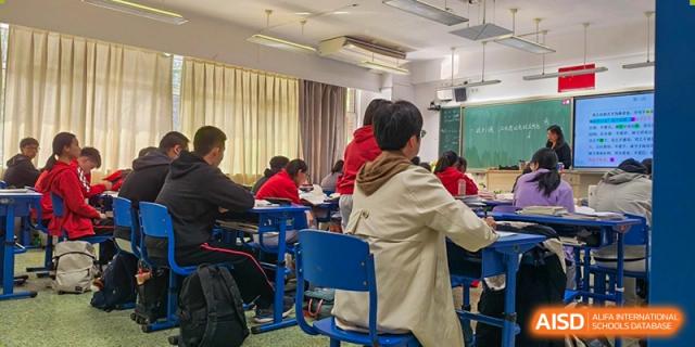 Chengdu Experimental Foreign Languages School International Department students focused on their work at desks during a regular class, with a teacher walking through the aisles.