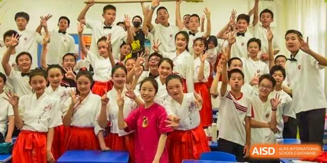 A large group of excited Chengdu Experimental Foreign Languages School International Department students cheering and posing for a group photo in bright attire.