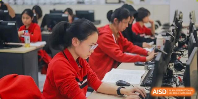 Chengdu Experimental Foreign Languages School International Department students, wearing red uniforms, intently working on computers in a lab.