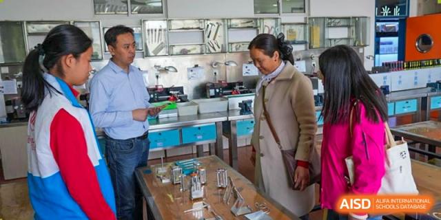 An instructor showing a Chengdu Experimental Foreign Languages School International Department student how to use laboratory equipment and glassware in a science lab.