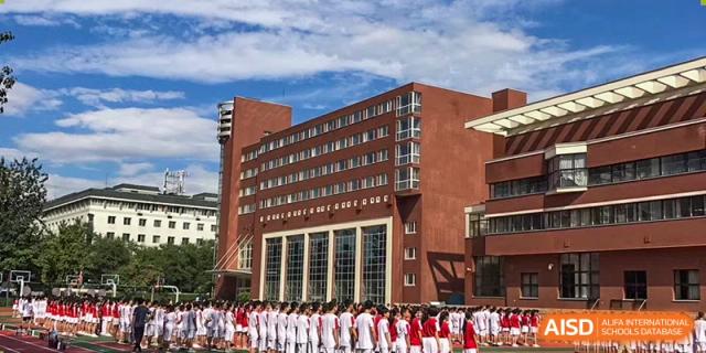 Exterior view of a main academic building at Chengdu Experimental Foreign Languages School International Department with a large group of students in uniform standing in front.
