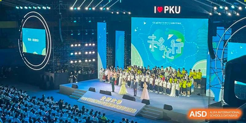 A large, lively performance or assembly at Chengdu Experimental Foreign Languages School International Department taking place on a large stage with "I ❤️ PKU" visible on the screen.