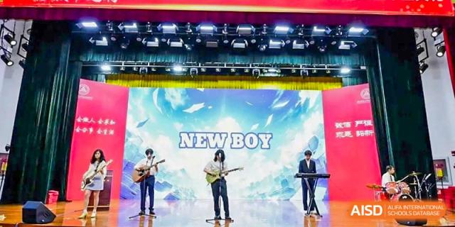 A band of Chengdu Experimental Foreign Languages School International Department students performing modern music on an illuminated stage with the text "NEW BOY" on the screen.