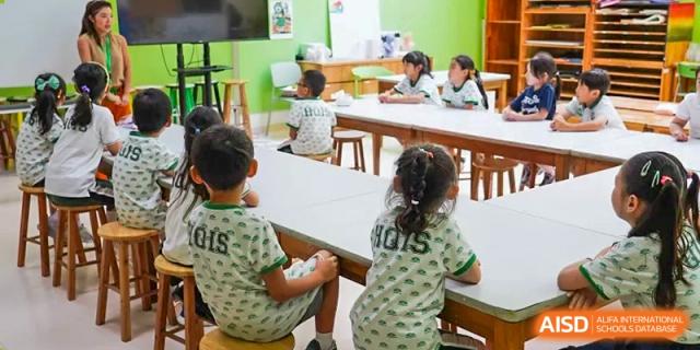 Young students seated at tables, working on tasks in a bright classroom setting at Shanghai Hongqiao International School.