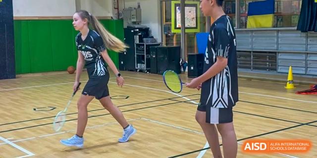 Two students playing badminton on an indoor sports court at Shanghai Hongqiao International School.