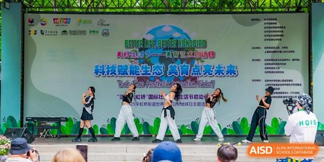 Students performing a dance or martial arts routine on a stage during a school event or conference at Shanghai Hongqiao International School.