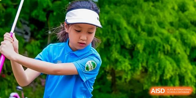 A close-up portrait of a female student wearing a white cap and a blue polo shirt with a school logo, likely at a sports event at Shanghai Hongqiao International School.