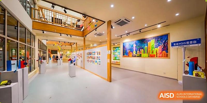 A bright, modern art gallery or exhibition space with colorful student work displayed on the walls at Shanghai Hongqiao International School.