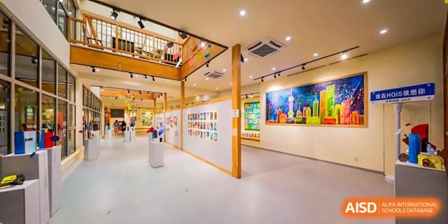 A bright, modern art gallery or exhibition space with colorful student work displayed on the walls at Shanghai Hongqiao International School.