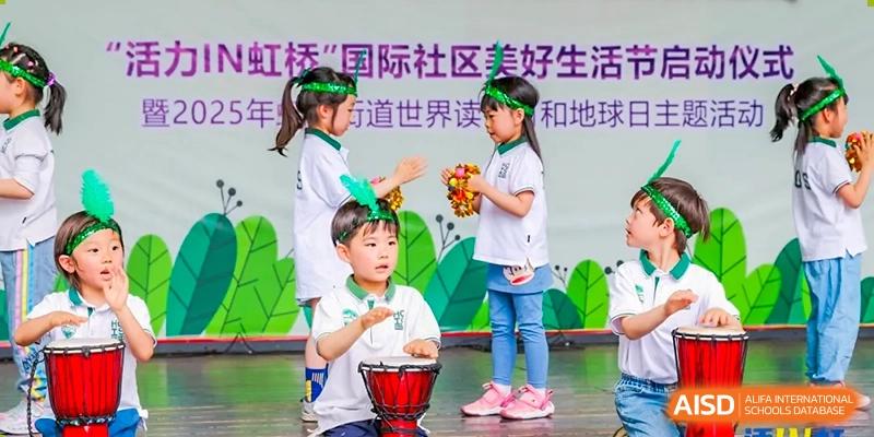 Young children performing on stage with small drums during a cultural or festive event at Shanghai Hongqiao International School.