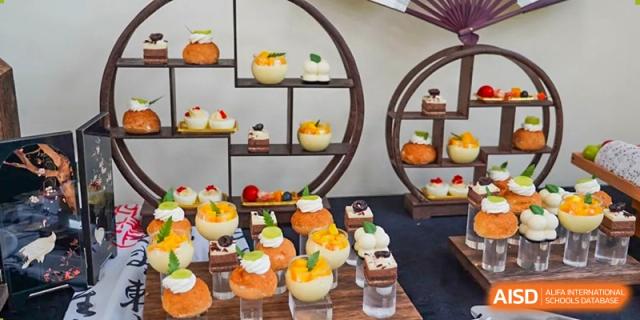 A decorative dessert display with small cakes, tarts, and fruit cups, likely for a special event at Shanghai Hongqiao International School.