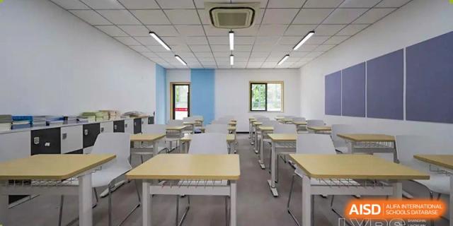 An empty, clean, and modern classroom at Shanghai Liaoyuan Bilingual School with rows of light-colored desks and chairs.
